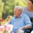 A caregiver takes a senior outside to visit a garden, highlighting one idea for senior activities.