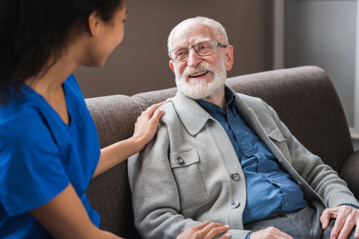 A caregiver kindly puts a hand on an older client's shoulder, representing the effect that quality personal care can have in Angola